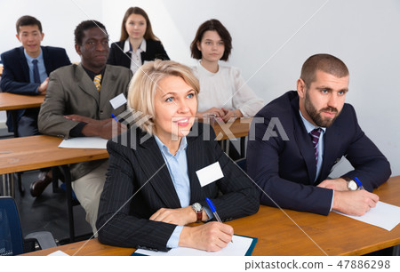 International group of business people listening to presentation at tables International group of business people listening to presentation at tables 47886298