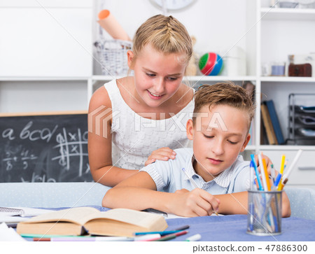 Girl is explaining to boy how to solve homework Girl is explaining to boy how to solve homework 47886300