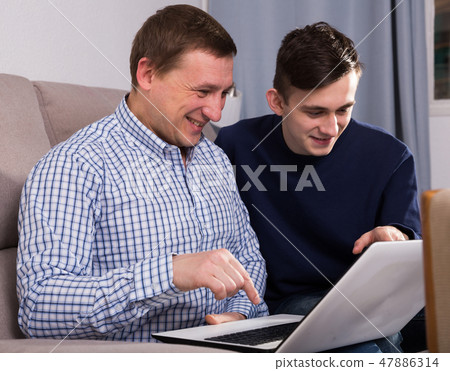 Guy with his father are resting and looking in notebook 47886314