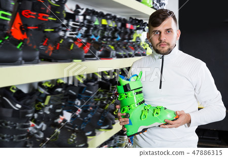 Handsome sporty guy looking for modern ski boots 47886315