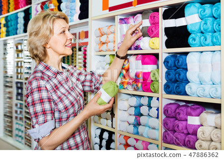 Mature glad woman customer picking various yarn Mature glad woman customer picking various yarn 47886362