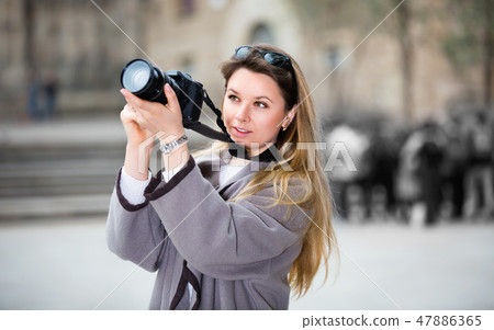 Girl holding camera in hands and photographing in the city Girl holding camera in hands and photographing in the city 47886365
