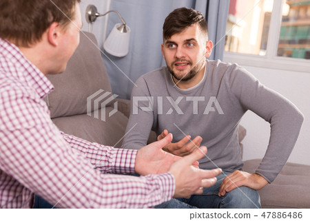 Guy lively discussing with friend on couch 47886486