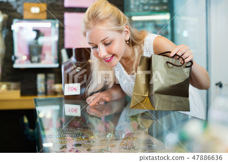 Portrait of young woman standing next to glass showcases 47886636