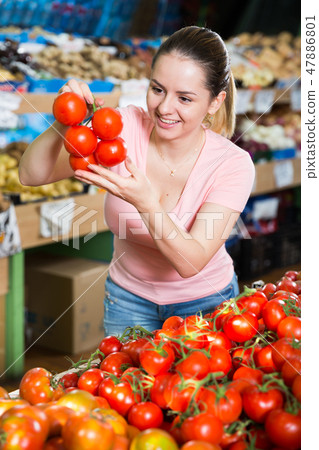 Young woman choosing tomatoes 47886801