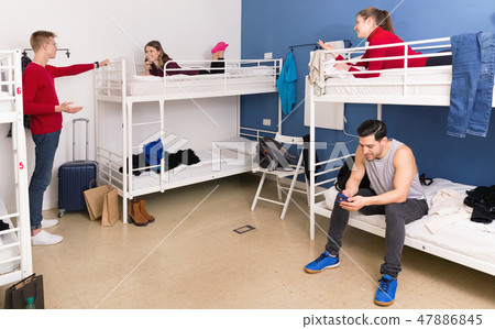 Young men and women friendly interacting while staying in modern comfy hostel 47886845