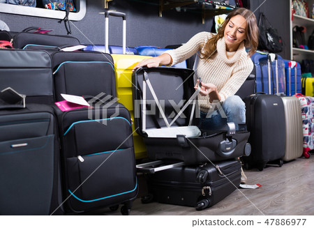 Young female purchasing travel suitcase 47886977