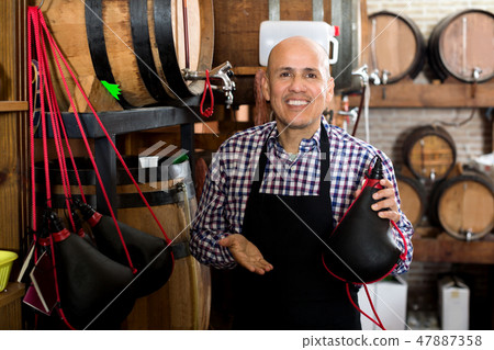 Seller holding spanish bota bag for wine 47887358