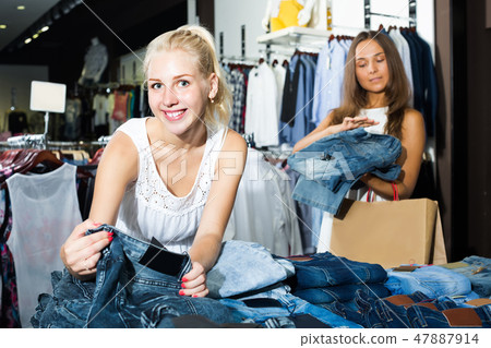 two women picking new pair of jeans in fashion department two women picking new pair of jeans in fashion department 47887914