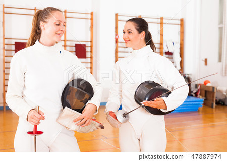 Active young women fencers in uniform talking at fencing room 47887974