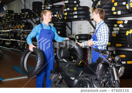 Two smiling males colleagues working with motorcycle tires 47888158