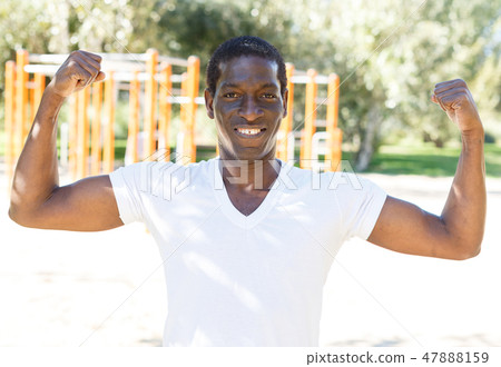 Smiling active african american man standing and posing in park Smiling active african american man standing and posing in park 47888159