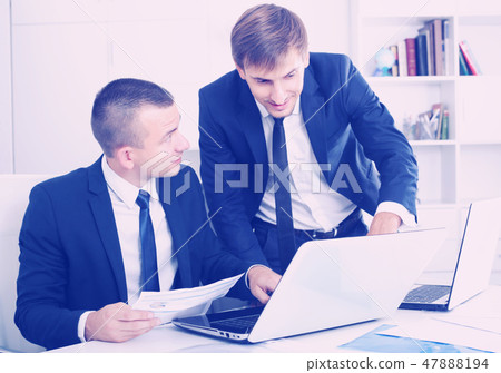 cheerful two males coworkers working in firm office 47888194