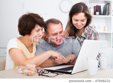 Daughter with parents searching documents on laptop 47888222