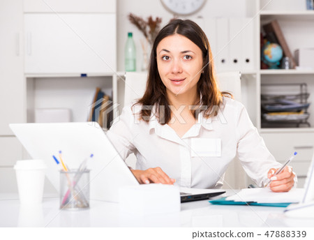 Young woman working with laptop and papers at the office Young woman working with laptop and papers at the office 47888339
