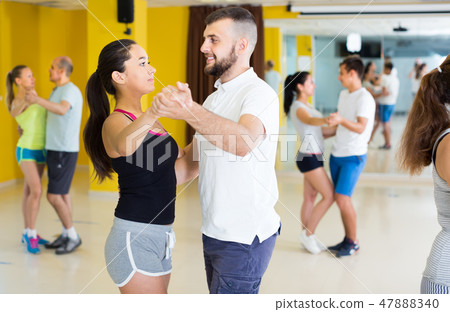Smiling dancing couples learning salsa Smiling dancing couples learning salsa 47888340