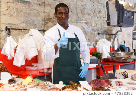 Male shop assistant selling fresh fish 47888392