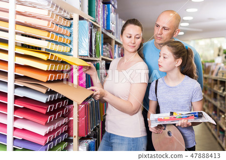 Young family with schoolgirl choosing school accessories in shop Young family with schoolgirl choosing school accessories in shop 47888413