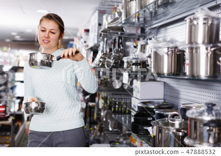 Young female is choosing modern stewpot for her kitchen 47888532
