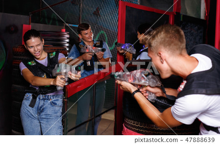 Portrait of friends standing with laser guns during laser tag game in dark room 47888639