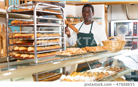 Baker working behind counter in bakeshop 47888655