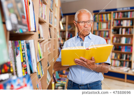 Focused elderly man looking for information in books in bookstore 47888696