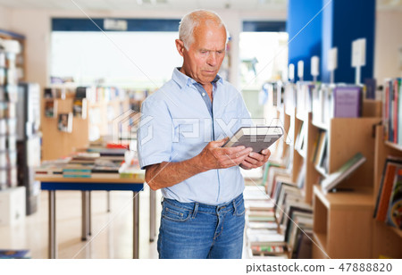 man absorbedly searching for interesting books man absorbedly searching for interesting books 47888820