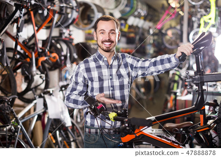 man checks bicycle handlebar in shop when choosing bike man checks bicycle handlebar in shop when choosing bike 47888878