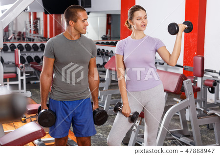 Sporty guy and girl posing with dumbbells 47888947