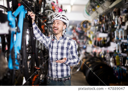 Man in helmet chooses convenient bike Man in helmet chooses convenient bike 47889047