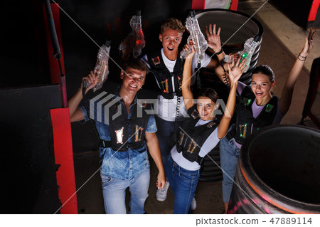 friends playing laser tag game with laser guns near tires friends playing laser tag game with laser guns near tires 47889114