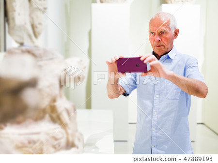 Man photographing sculptures in museum Man photographing sculptures in museum 47889193