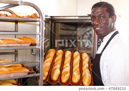 Baker showing tray of fresh bread 47889232
