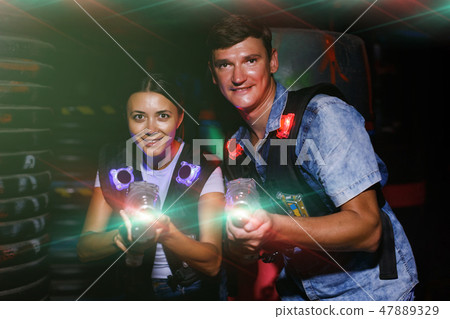 couple holding colored laser guns during laser tag game 47889329