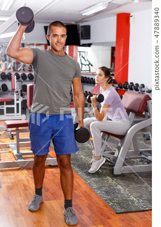 Man doing exercises with sports dumbbells Man doing exercises with sports dumbbells 47889340