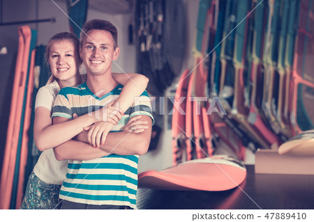 Young couple is posing in surfboard store on the beach. Young couple is posing in surfboard store on the beach. 47889410