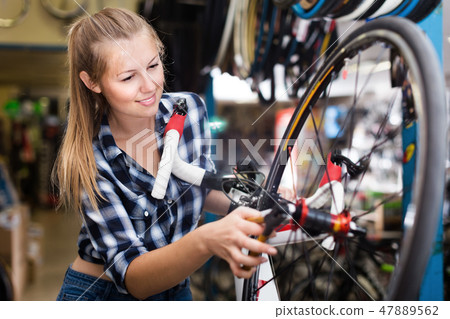 Young woman master is repairing wheel of bicycle 47889562