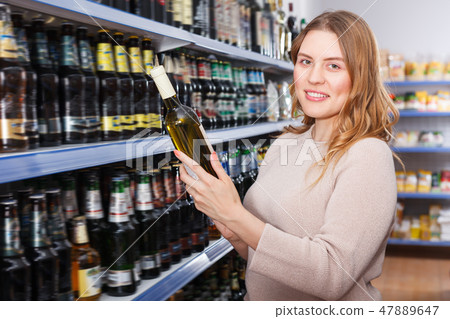 Portrait of adult woman buying bottle of wine Portrait of adult woman buying bottle of wine 47889647