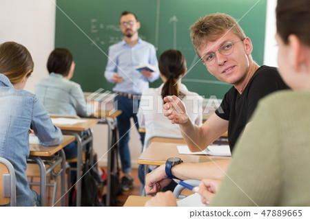 Young girl and boy are sitting at the desk and talking in time lecture in the classroom 47889665