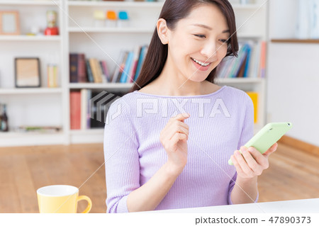 看智能手機的婦女在屋子裡 看智能手機的婦女在屋子裡 47890373