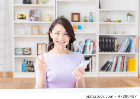 Woman looking at smartphone in the room Woman looking at smartphone in the room 47890487