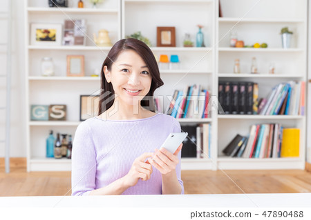 看智能手機的婦女在屋子裡 看智能手機的婦女在屋子裡 47890488