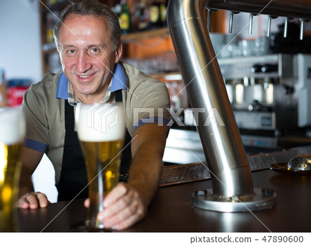 Smiling barman is offering unbottled beer to next client 47890600