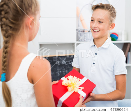 Girl is giveing a gift to friend on his birthday Girl is giveing a gift to friend on his birthday 47890624