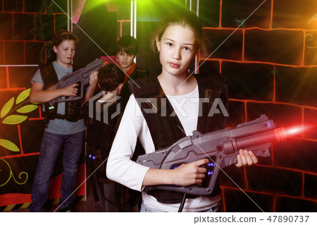 Cheerful teen girl standing with laser pistol in dark lasertag r 47890737