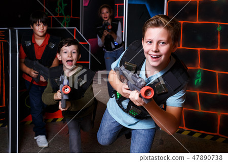 boy aiming laser gun at other players during lasertag game 47890738