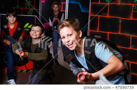 Portrait of preteen boy with laser gun having fun on dark lasertag arena Portrait of preteen boy with laser gun having fun on dark lasertag arena 47890739