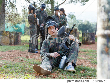 Man wearing uniform and holding gun ready for playing with friends paintball outdoor Man wearing uniform and holding gun ready for playing with friends paintball outdoor 47890740