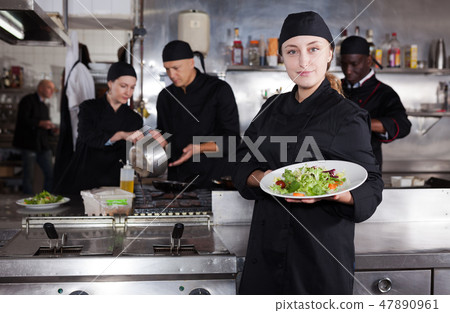 Confident female chef with a team of cooks in restaurant kitchen Confident female chef with a team of cooks in restaurant kitchen 47890961