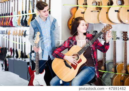 teenage customers comparing amp and acoustic guitar in guitar shop teenage customers comparing amp and acoustic guitar in guitar shop 47891482